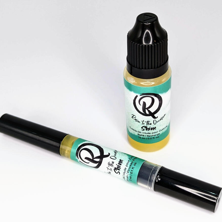 A cuticle brush pen and dropper bottle with a shimmering yellow oil inside.
