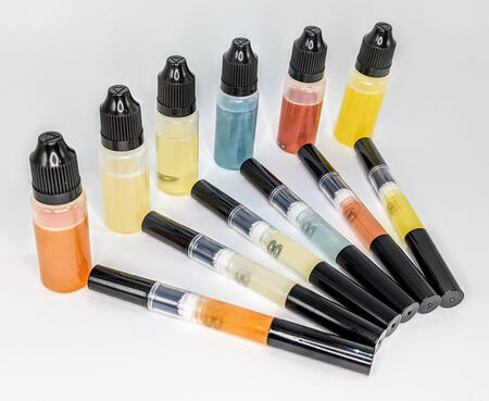 A display of cuticle brush pens and dropper bottles filled with colourful oils.